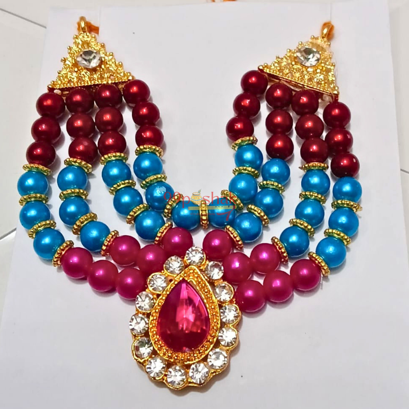 A traditional Indian jewelry necklace set featuring red, blue, and magenta pearl-like beads with gold-plated trident-shaped tops and a central teardrop pendant, displayed on a white background.