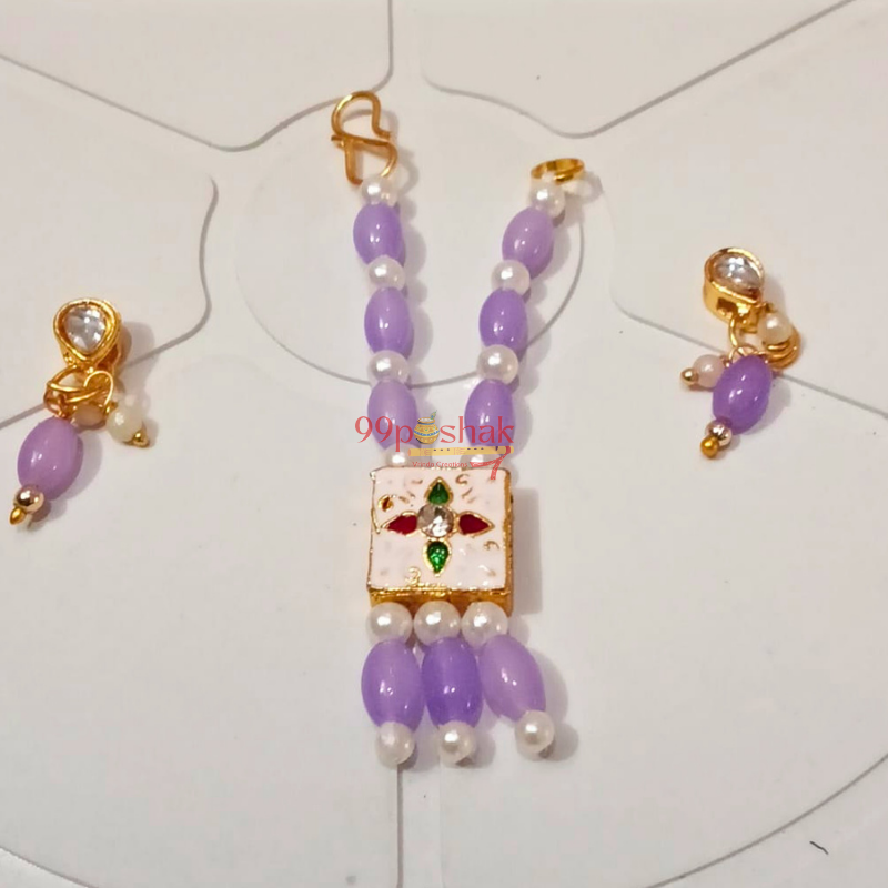 A traditional Indian jewelry set featuring a purple beaded necklace with a central white enamel pendant decorated with red and green stone accents, accompanied by matching gold earrings with purple beads and pearl-like white beads, displayed on a white background.