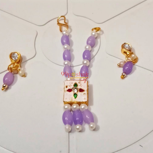 A traditional Indian jewelry set featuring a purple beaded necklace with a central white enamel pendant decorated with red and green stone accents, accompanied by matching gold earrings with purple beads and pearl-like white beads, displayed on a white background.